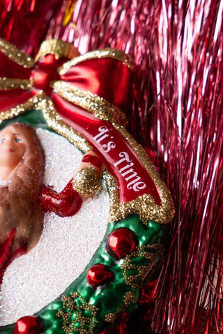 Close-up of the words 'it's time' on a christmas tree decoration displayed on top of some red tinsel.