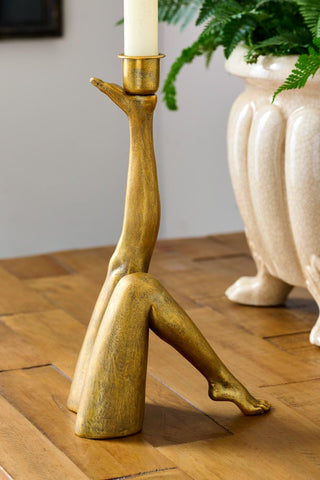 Close-up image of the Kick Leg Candle Holder displayed on a wooden sideboard with a planter in the background.