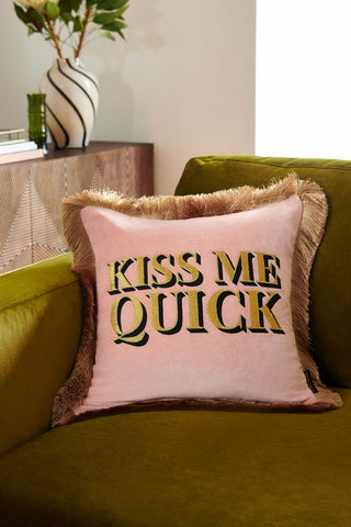 Lifestyle image of the Kiss Me Quick Velvet Fringe Feather Filled Cushion on a sofa