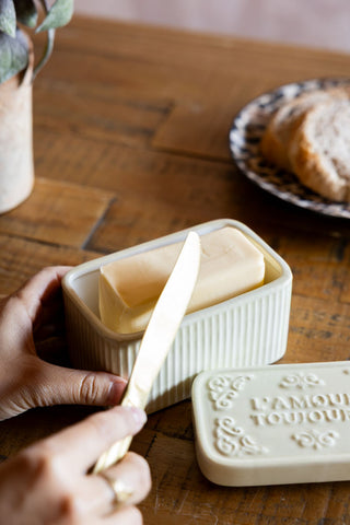 The L'Amour Toujours Butter Dish shown with someone scraping butter from the dish. 