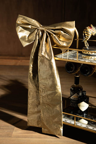 The Large Gold Bow Christmas Decoration styled on the edge of a bar cart.