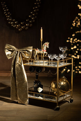 The Large Gold Bow Christmas Decoration styled on a bar cart with various accessories.