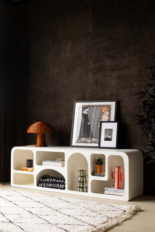 Lifestyle image of the Large White Alcove Shelf with various decorative accessories displayed inside and on the top. The shelf is in front of a dark wooden wall with a rug in front of it.