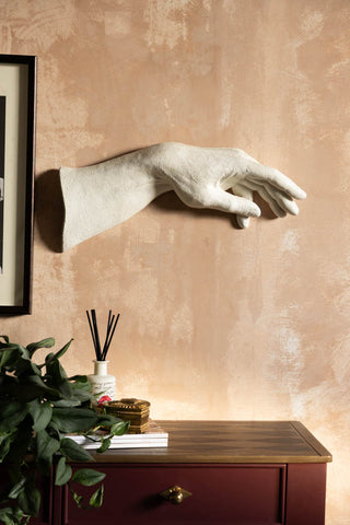 The Large White Helping Hand Wall Art shown on a plaster wall above a burgundy and wood console table. 