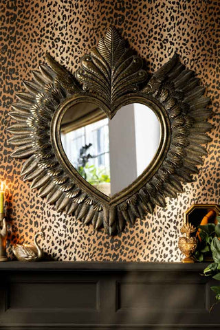 The Large Winged Milagro Mirror styled on a leopard print wall with various accessories on a fireplace beneath.