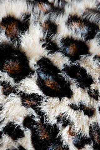 Close up image of the Leopard Faux Fur Throw, focusing on the abstract leopard print and the brown and black tones of the leopard spots against the cream background.