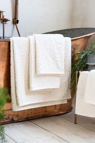 Leopard Jacquard Towels in Almond shown as a group of all sizesagainst a copper bath.