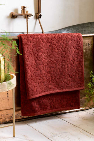 The large bath sheet Leopard Jacquard Towel in Burnt Brick shown on a copper bath. 