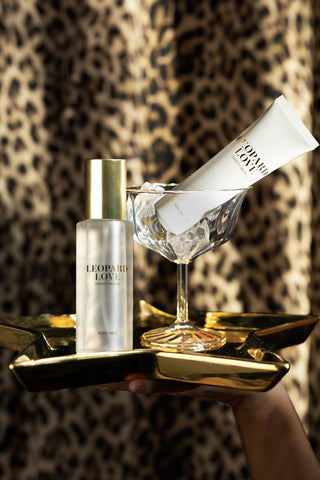 The body mist and hand cream from inside the Leopard Love Hand & Body Beauty Cracker, styled on e glass/star shaped tray on a model's hand.