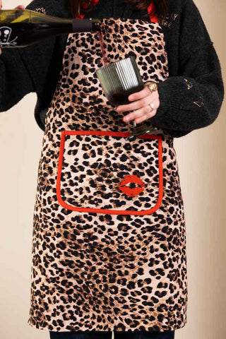 Person wearing a leopard print apron with a red pocket design, holding a bottle.