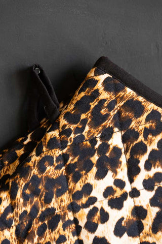 Close-up of the hook on the Leopard Love Print Oven Mitts in front of a black wall.