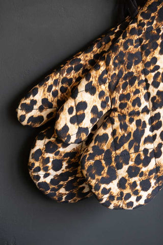 The Leopard Love Print Oven Mitts on a dark surface.