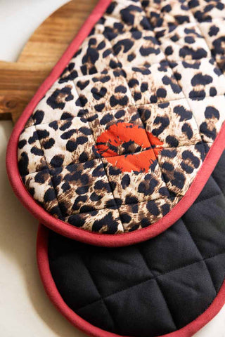 Close-up of the Leopard Love Print & Red Detailing Oven Gloves displayed on a wooden serving board.