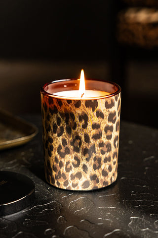 The Leopard Love Scented Candle lit and displayed on a dark leopard print surface.