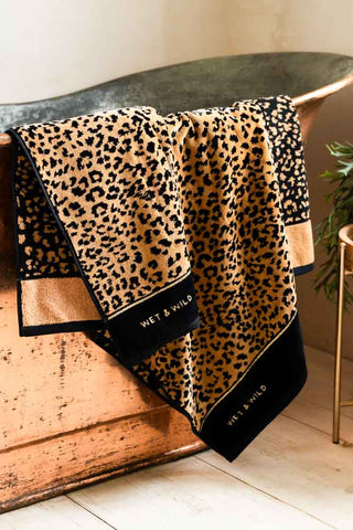 Image of the Wet & Wild Leopard Print Bath Towel draped over a copper bath.