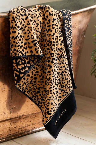 Closer image of the Wet & Wild Leopard Print Bath Towel shown on the edge of a copper bath. 
