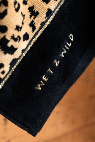 Detail shot of the border of the Wet & Wild Leopard Print Bath Towel, showing the "Wet & Wild gold stitching