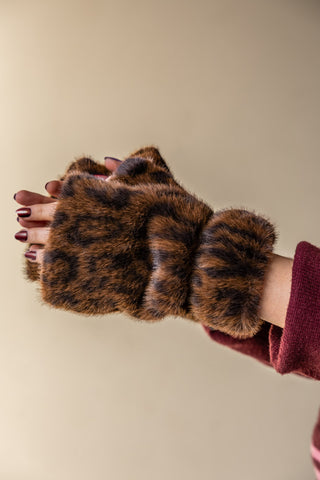 The Leopard Print Faux Fur Handwarmers being worn by a model, holding their hands up in front of a plain wall.