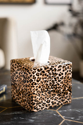 Leopard Print Tissue Box Holder shown on a marble table with a tissue. 