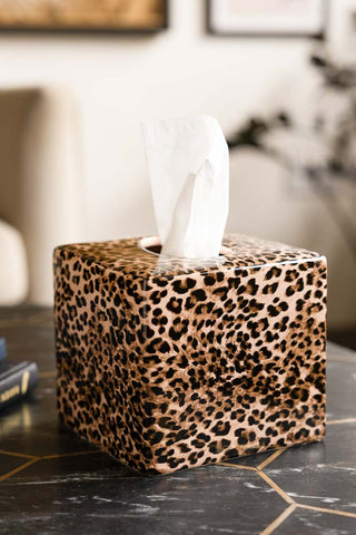 The Leopard Print Tissue Box Holder shown on a marble coffee table in a living room. 