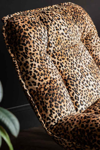 Close-up of the Leopard Print Velvet Swivel Chair next to a plant.