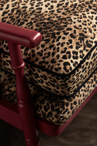 The dark red arm and leopard upholstery with black piping. 