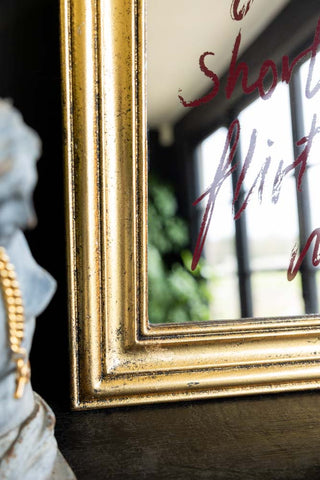A close up shot of the corner of the gold frame of the Life Is Short, Flirt With Me Mirror. 