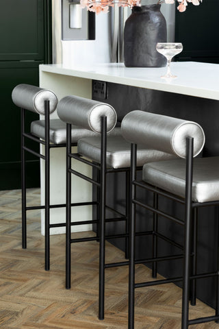 Image of 3 of the Metallic Silver Roll Back Bar Stool lined up against a black kitchen island.