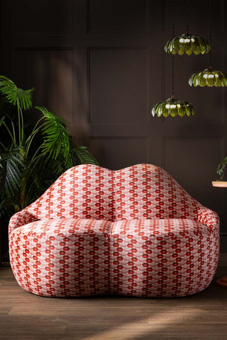 The Lips Print Velvet Lips Sofa styled in front of a dark wall with a plant and cluster light.