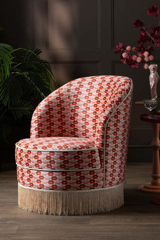 The Lips Tassel Swivel Chair styled with a table, some accessories and a plant.