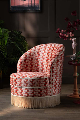 The Lips Tassel Swivel Chair in a dark room with a side table and various accessories.