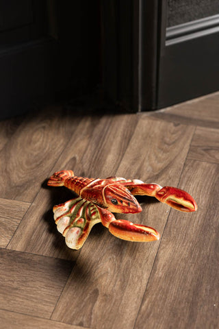 The Lobster Cast Iron Boot Jack on the floor by an open door.