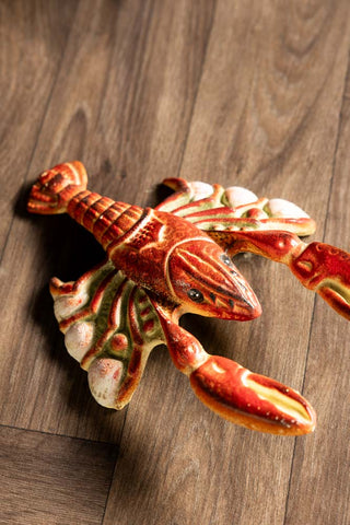 The Lobster Cast Iron Boot Jack on a wooden floor.