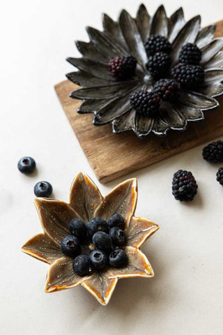 Large black lotus tray and a small ochre lotus dish styled with blueberries and blackberries.