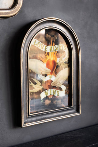 The Vintage-Style Love Wins Framed Wall Art seen from an angle, displayed on a dark wall.