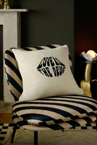 Image of the Love Is The Drug Knitted Lips Cushion on a chair