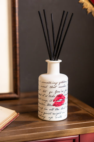 The Love Letters Reed Diffuser shown on harlequin wood console table against dark walls. 
