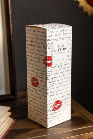 The box of the Love Letters Reed Diffuser, covered in the same love letter text and red lipstick kiss marks. 