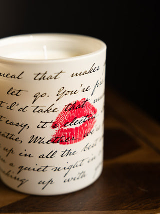 Close up of the Love Letters Scented Candle, showing the black love letter text and red kiss mark against the white votive. 