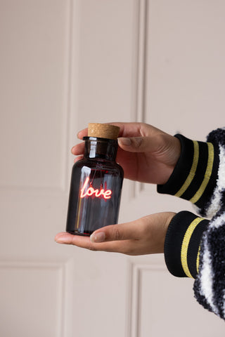 The Love Neon Bottle Light held in a model's hands.