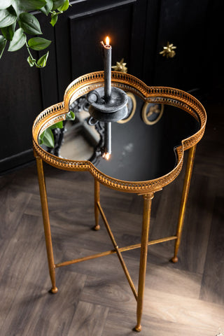Lucky Clover Mirrored Side Table shown against a black cabinet with a grey candle on the mirrored top. 