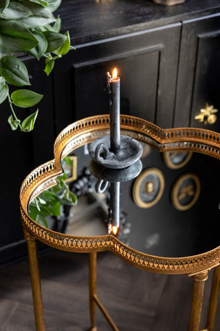 A closer detail of the Lucky Clover Mirrored Side Table, shown styled against a black cabinet with a grey candle on the top. 