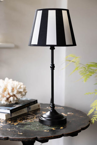 The Monochrome Bistro Table Lamp displayed on a round side table with some books and a coral ornament.