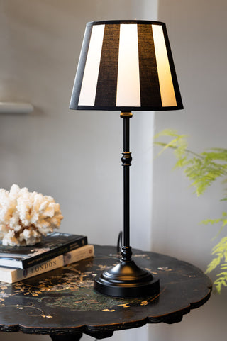 The Monochrome Bistro Table Lamp switched on and styled on a table with some accessories.