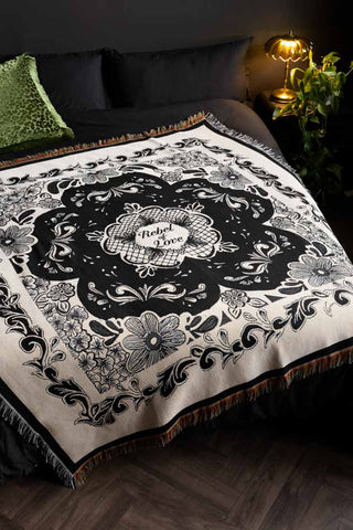 The Monochrome Forever Rebel Woven Throw, shown on a bed against black bed linen. 