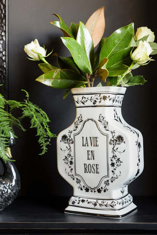 The Monochrome La Vie En Rose Vase styled with flowers and greenery inside, displayed on a black surface with another vase.