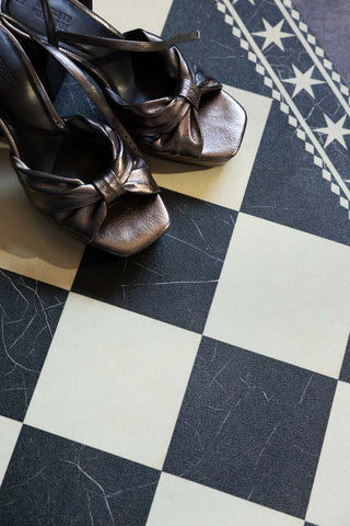 A close up shot of the Monochrome Marble Tile Effect Durable Runner, shown with bronze metallic platform heels. 