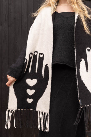 A monochrome wool-style scarf with a black hand motif on one side and white hand motif on the other