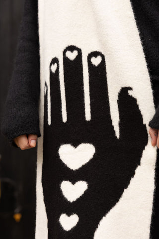 A close-up of black hand detailing on a black and white wool-style scarf 