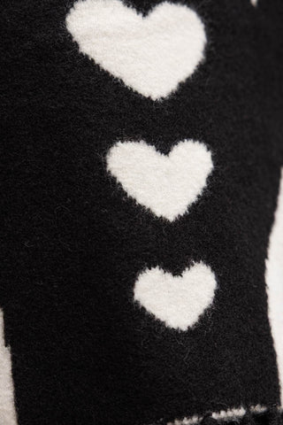 A close-up of white hearts detailing on a monochrome wool-style scarf 